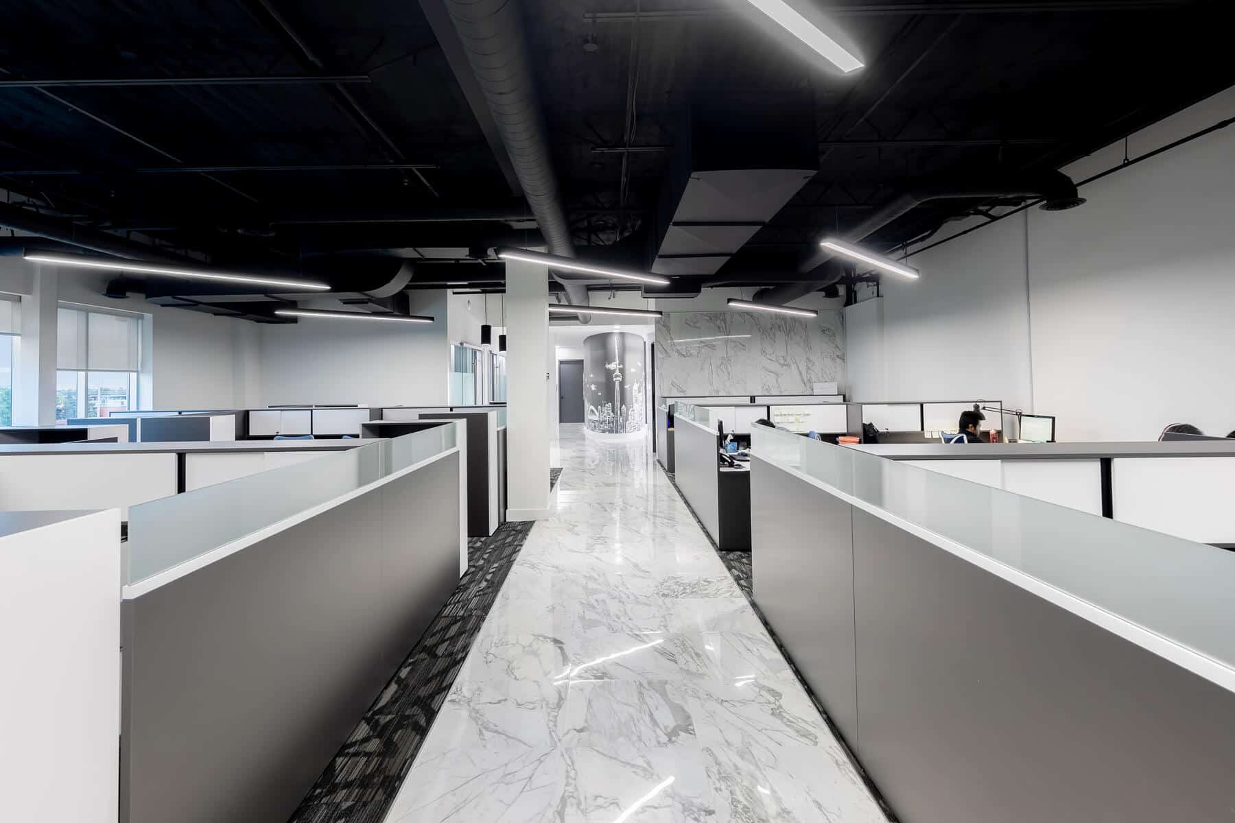 Intérieur de bureau moderne avec une décoration en noir et blanc, comprenant des bureaux avec séparateurs de cabines, des sols en marbre et des plafonniers.