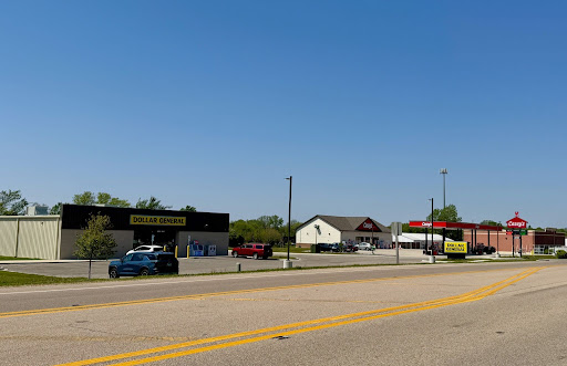 Dollar General à gauche et Casey's à droite - juste en face l'un de l'autre, sur la route principale en face d'eux qui traverse la ville. Parking vide devant Dollar General sous un ciel bleu.
